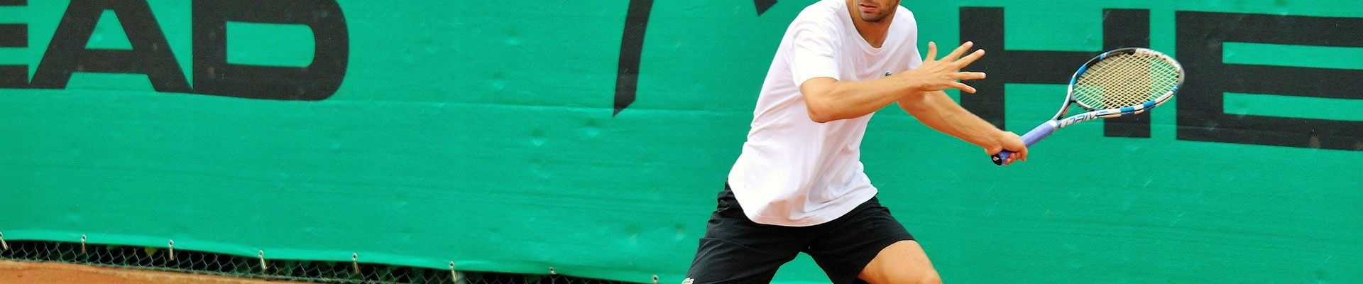 Tennisspieler schlägt eine Vorhand auf einem roten Sandplatz
